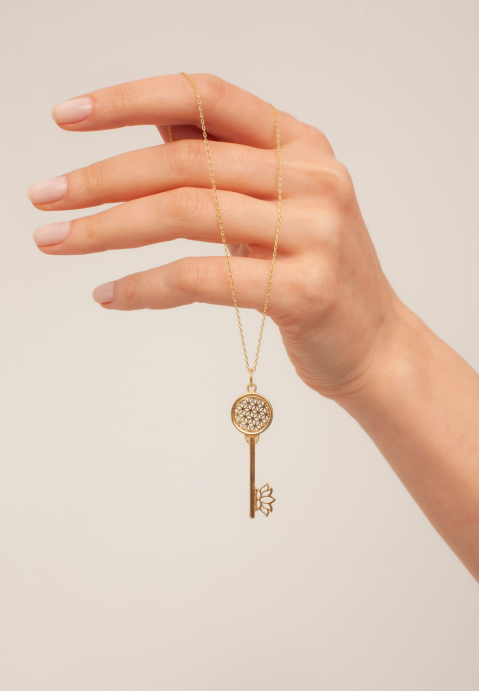Hand holding gold key pendant necklace