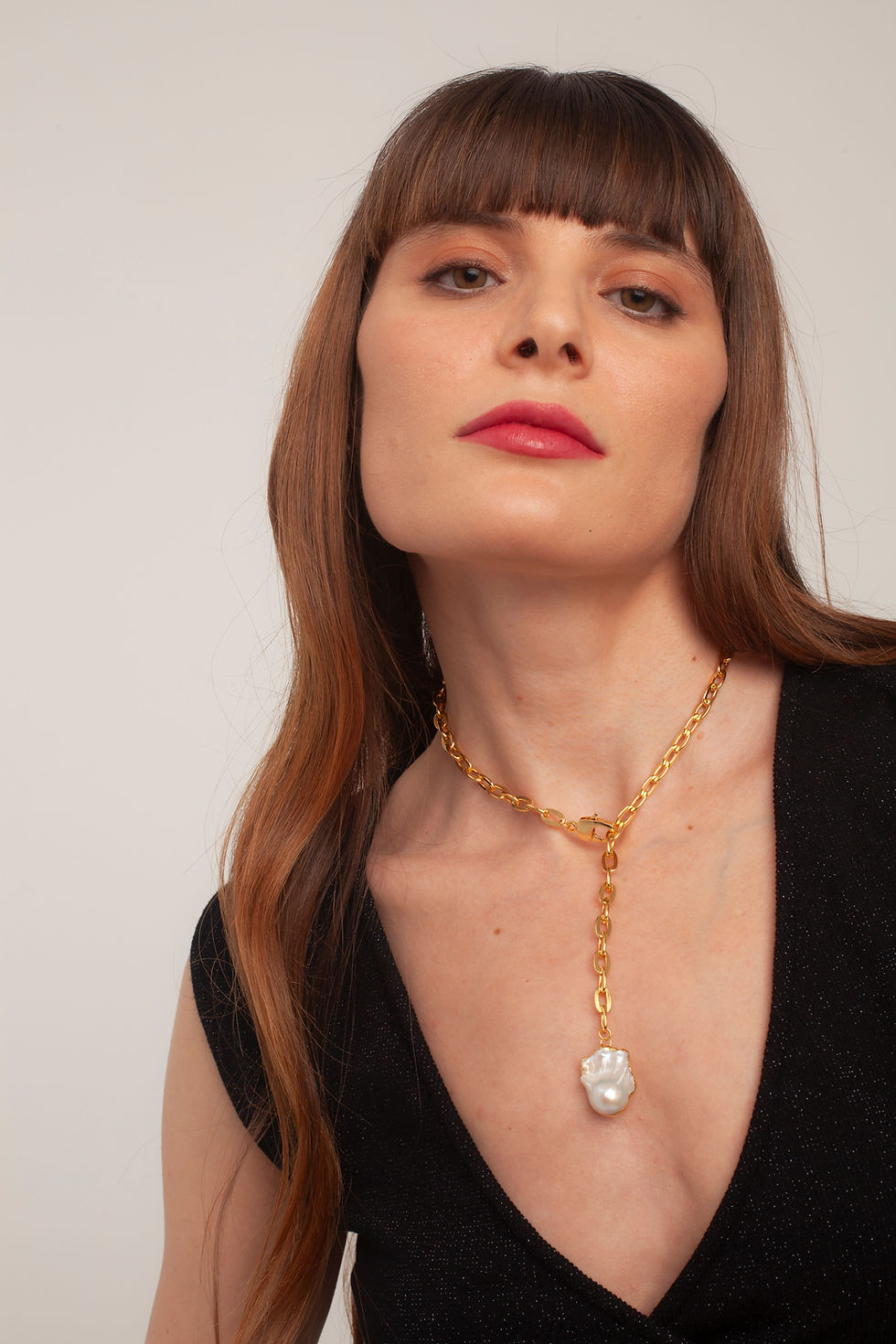 Woman wearing gold chain necklace with baroque pearl pendant
