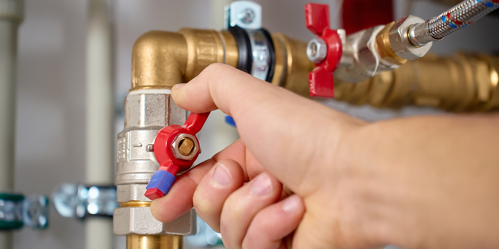 Hand turning a red valve on a water pipe system for plumbing.