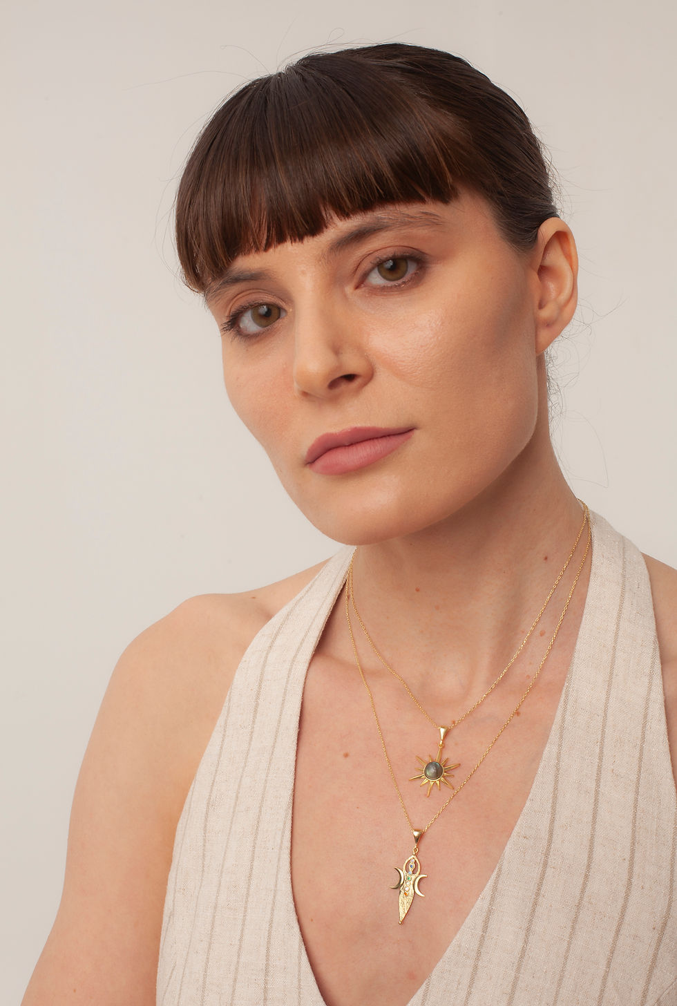 Woman wearing gold necklace with green gemstone pendant
