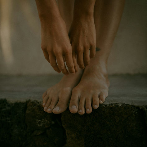 Woman standing with her hands over her feet