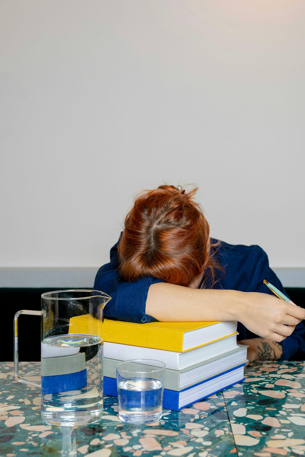 Woman sitting at a desk with her head over books