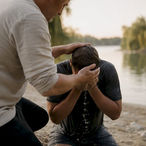 Water poured over hands outdoors at baptism