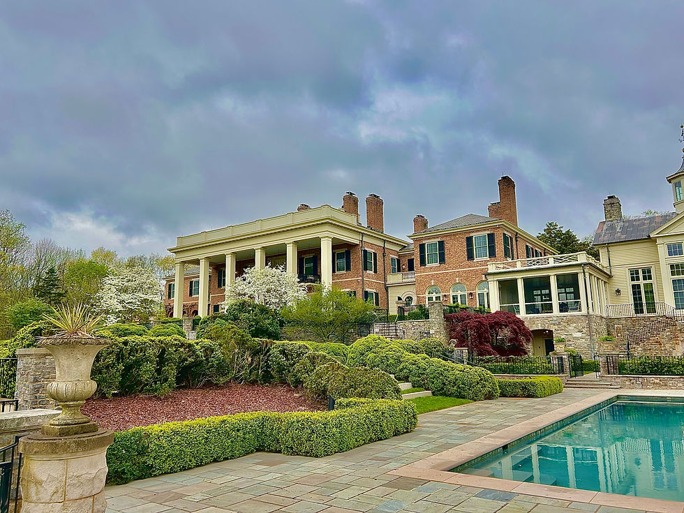 Elegant mansion with a pool, lush gardens, and cloudy sky. Our Projects.