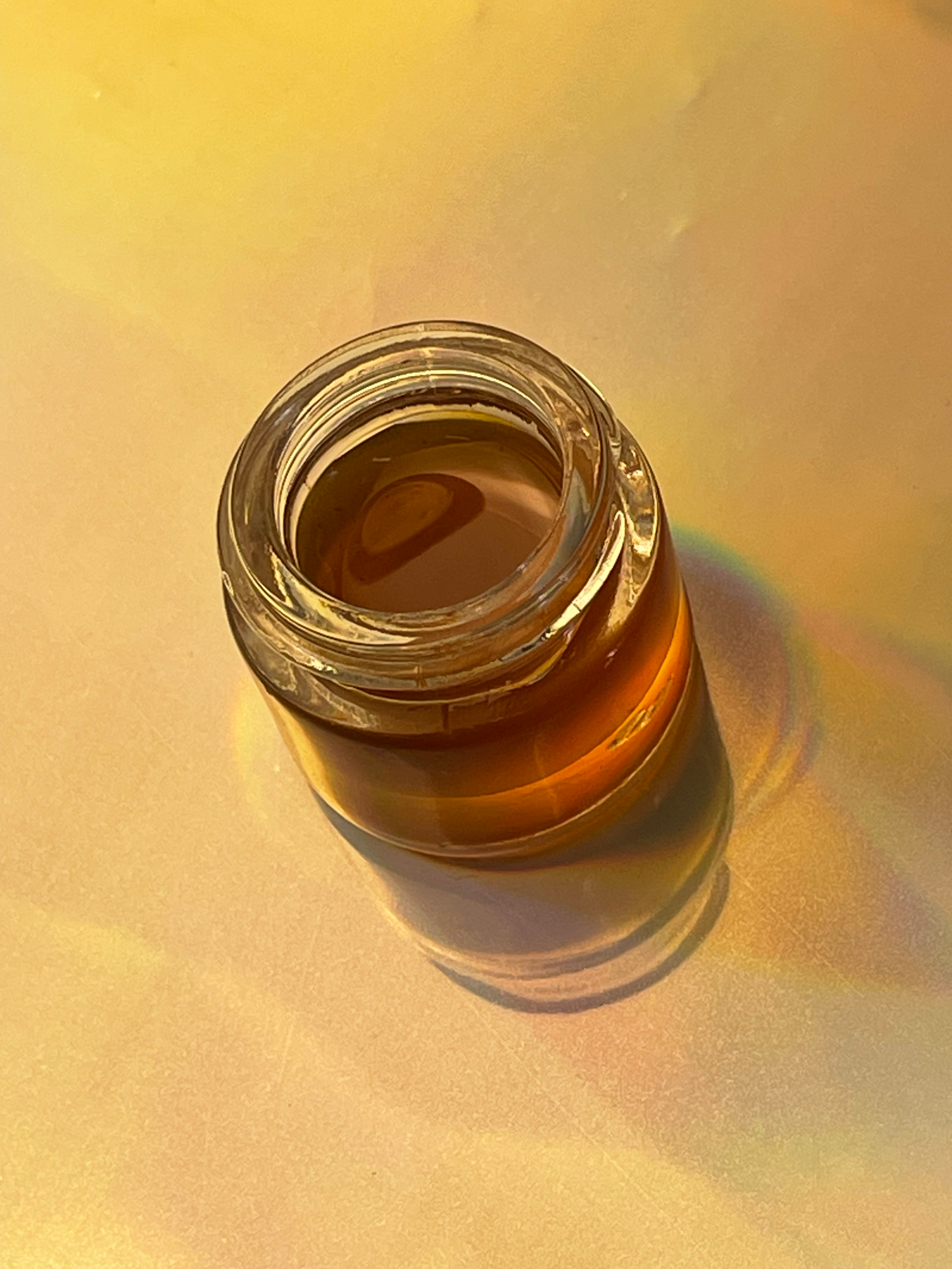 Mad Honey in a glass jar on a warm golden background