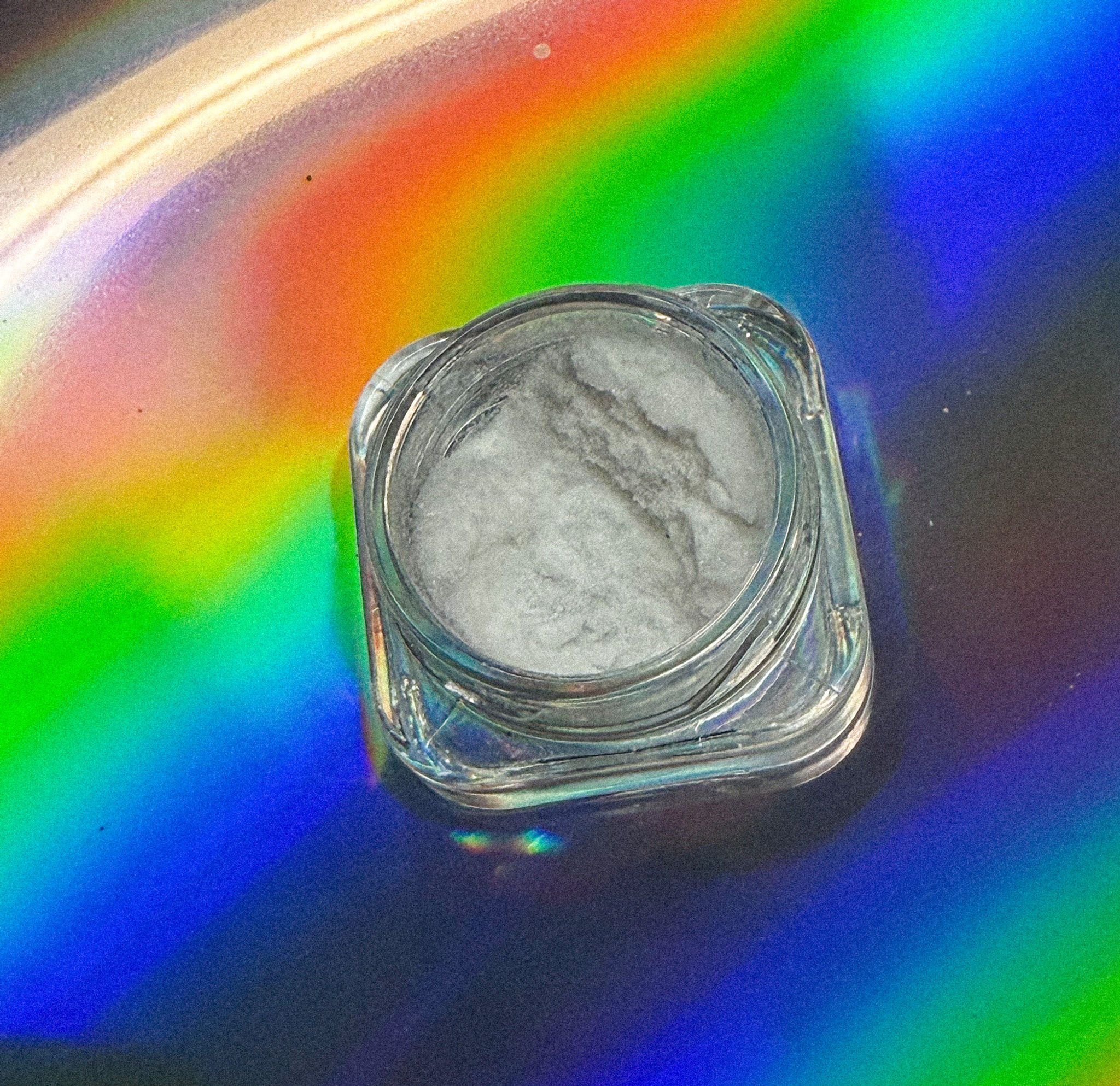 Pure Muscimol Isolate powder in a clear glass jar on a colorful reflective background.