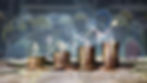 image of four increasing in size stacks of coins with a background image of a group of workers.