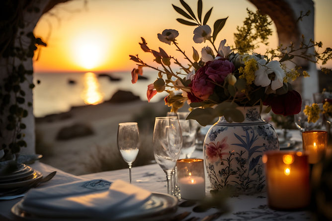 Sunset Linen and Uniform homepage image of a table setting in the foreground and a sunset over the ocean in the background.