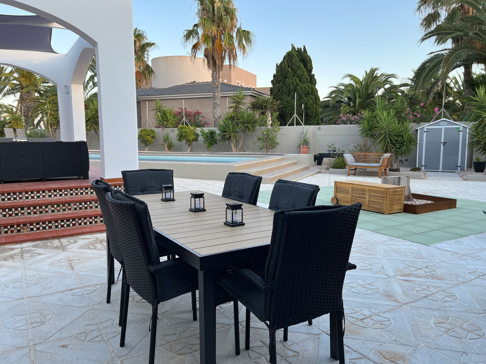 Outdoor dining area with table and chairs near a pool Villa de los Osos