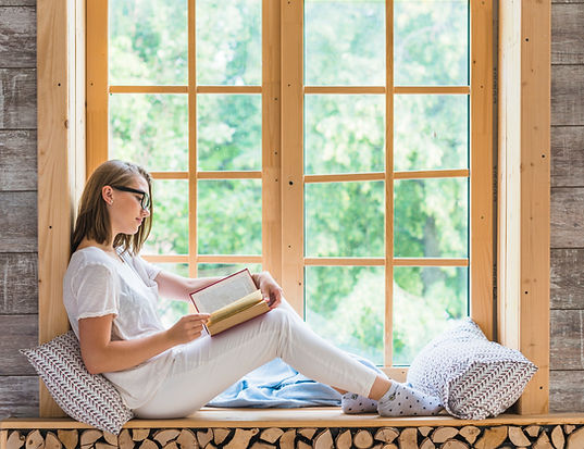 side-view-young-woman-reading-book-sitting-near-window-sill.jpg
