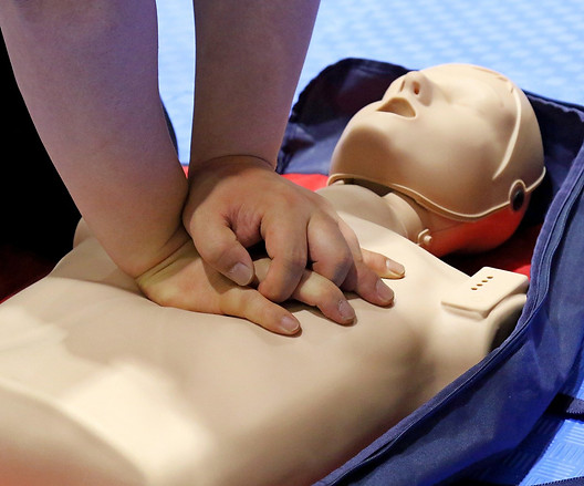 A person pressing down on a CPR dummy.