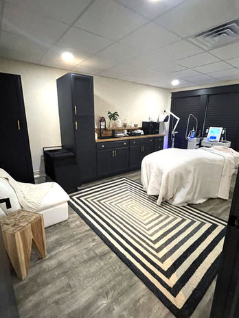 treatment room with client bed, chair, dresser and decor