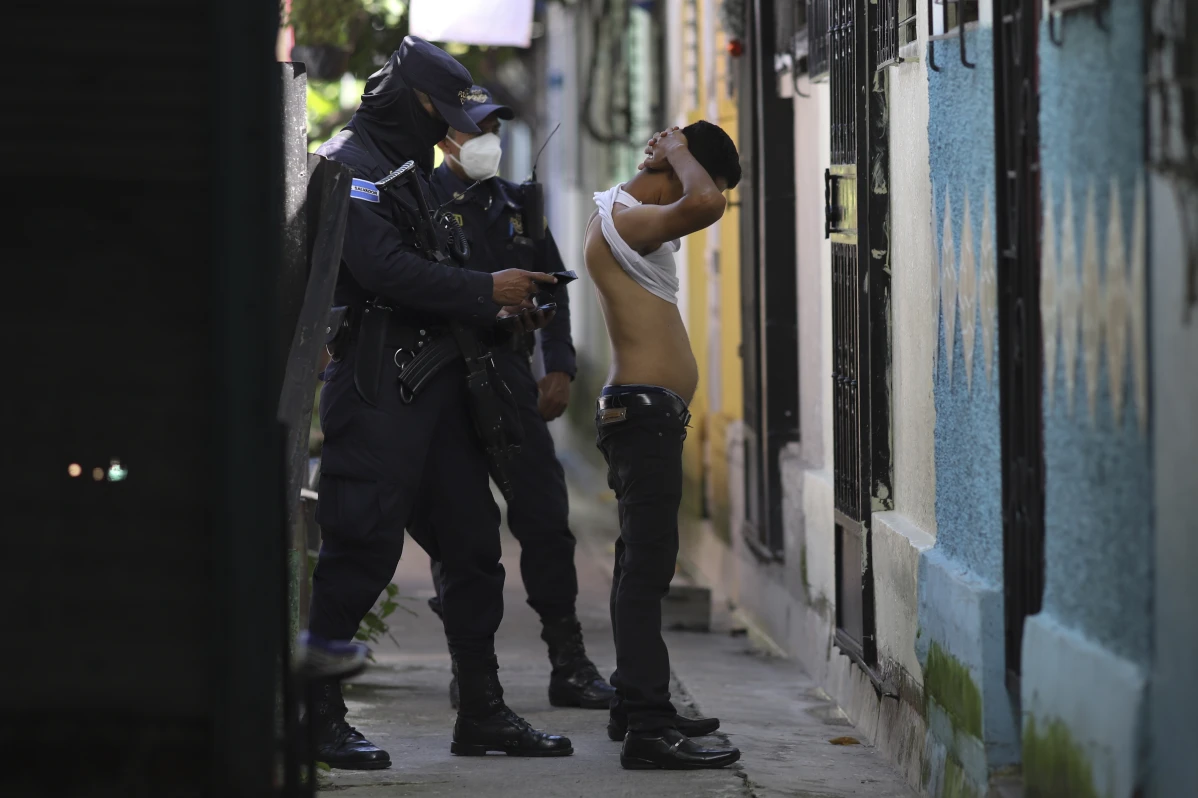 A police officer searches and checks the documents of a man living in Kiwanis Community, during a preventative patrol search of gang members in Soyapango, El Salvador, Tuesday, Aug. 16, 2022. A May 2023 report by the human rights organization Cristosal, tallied 153 incarceration deaths during the first year of the sate of emergency in El Salvador. No victim had been convicted of the alleged crime that put them behind bars. (AP Photo/ Salvador Melendez)