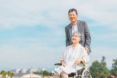 公園で車椅子に乗って散歩する高齢者夫婦