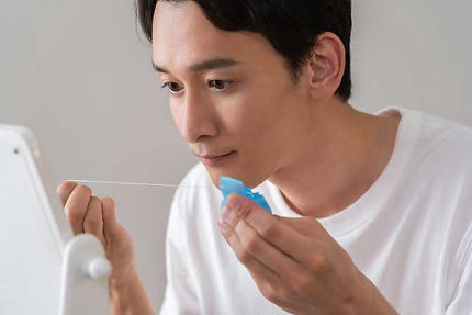 鏡を見てフロスをする男性