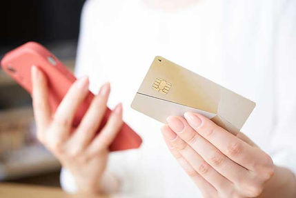 クレジットカードとスマホを持つ女性の手元