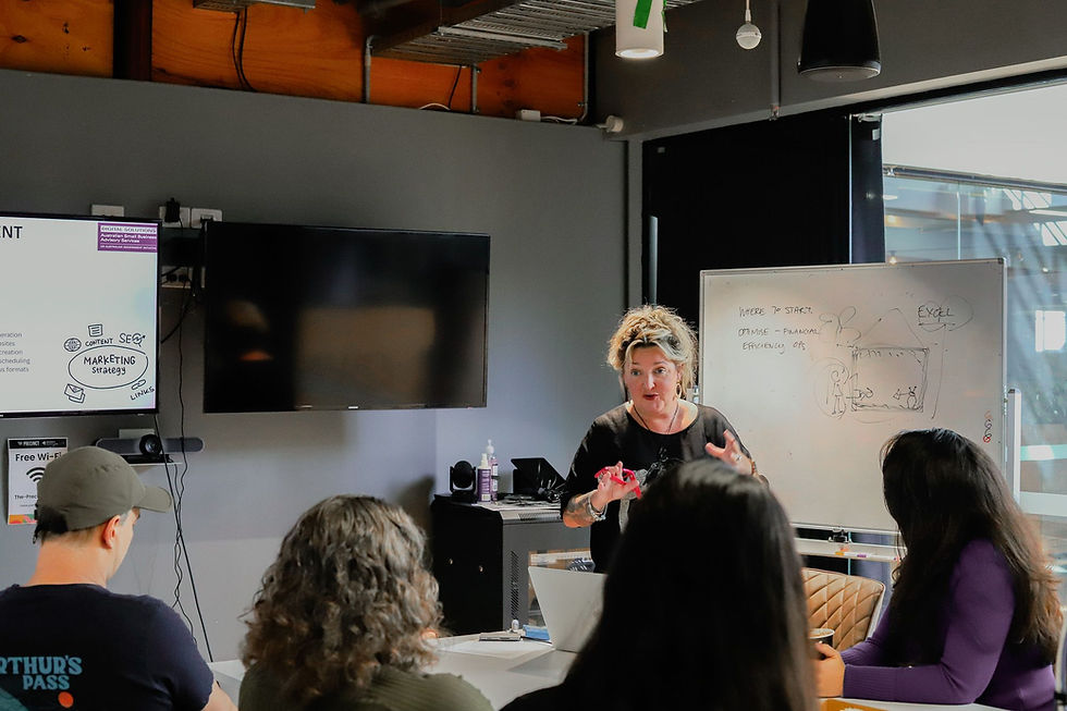 Corrie Dark,  a workshop facilitator, leads a session about technology, presenting to a small group in a modern office space.
