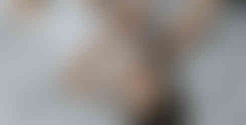 A happy child lies on the bed while getting dressed.