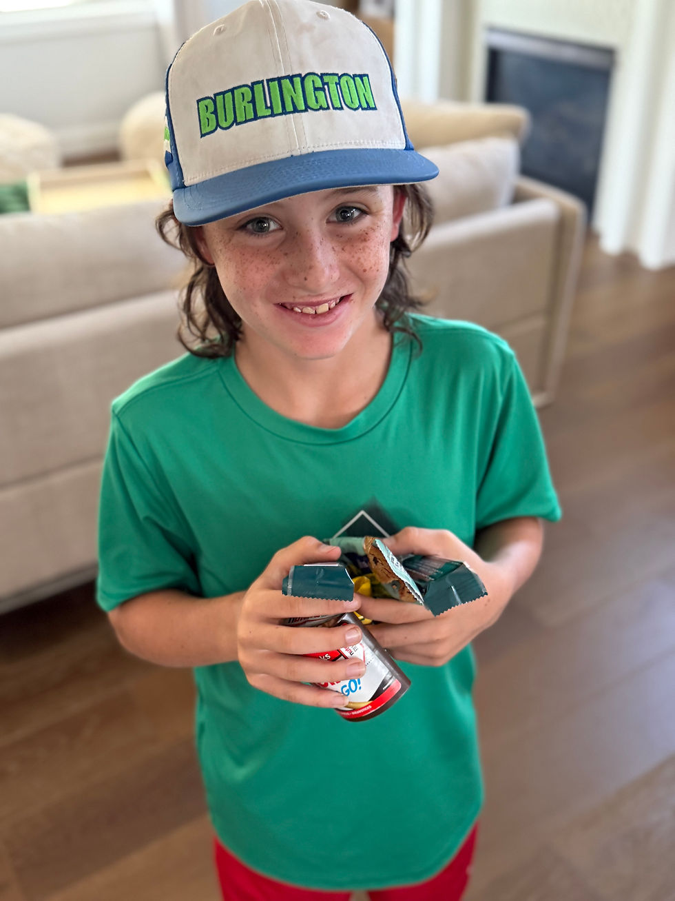 Smiling child in a green t shirt holding a handful of snacks