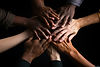 group-of-people-joining-hands-together-on-black-background-closeup-stack-of-hands-showing-