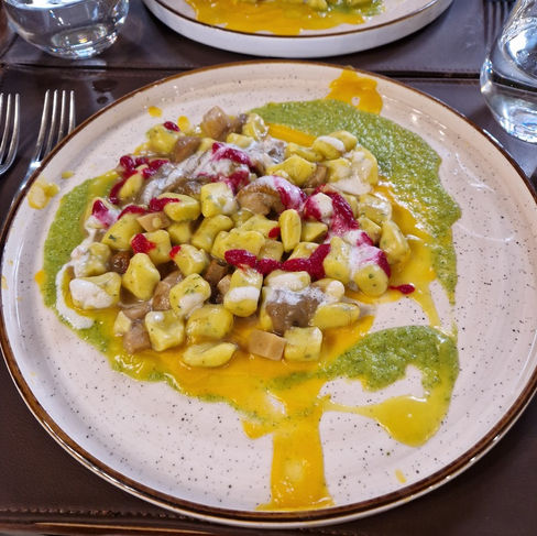 Sajtos-céklás gnocchi gombamártással és zöld pestoval tányéron, palermói étteremben