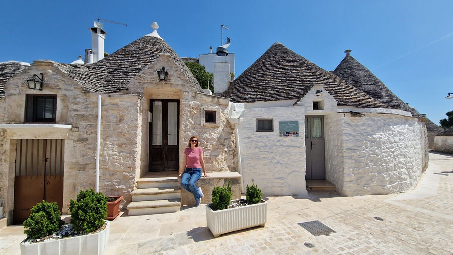 Alberobello házai előtt ül egy lány