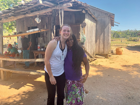 Rachel and Clara standing together with arms around each other in front of a wooden building on Clara’s property.