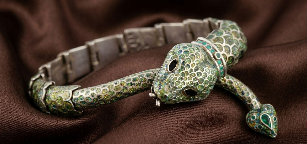 Pulsera en forma de serpiente con incrustaciones verdes y turquesa sobre tela marrón.