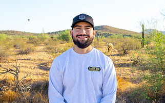 Saul Barajas, the owner, standing in front of a desert landscape smiling with his Arizona Gold Air shirt on.