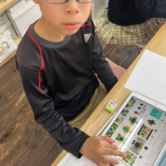 教室で眼鏡の男の子がタブレットで学習