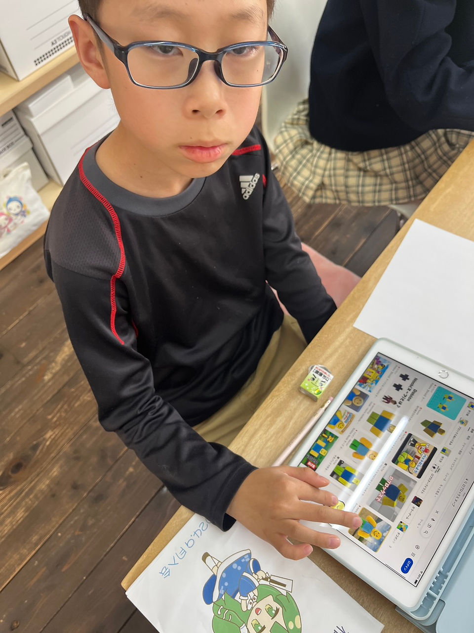 教室で眼鏡の男の子がタブレットで学習
