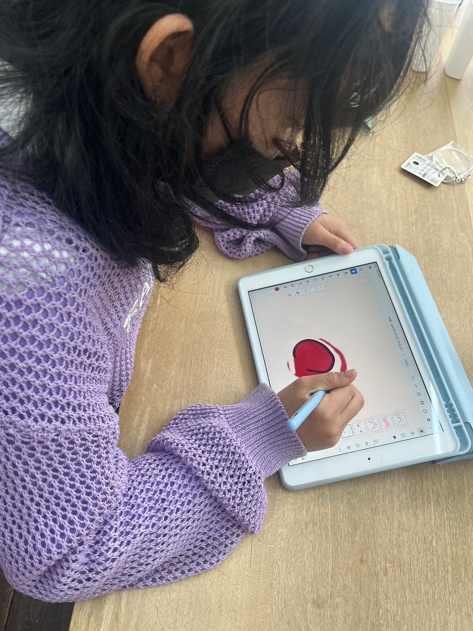 教室で子供がタブレットに赤いハートを描く
