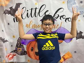 笑顔の子供が「A little boo」の背景でピースサイン。ハロウィーンの背景です。Kids