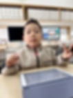 男の子がピースサイン、タブレットとMac、CONVERSE ジャケットを着て、学校の教室にいる