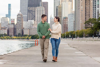 couple walking alongside the water at north avenue beach while posing for engagement photos photographed by Pamela l king photography