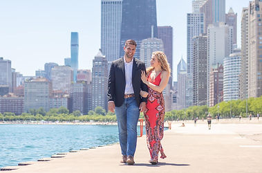 man and woman walking alongside the water at north avenue beach in chicago while posing for engagement photos photographed by Pamela l king photography