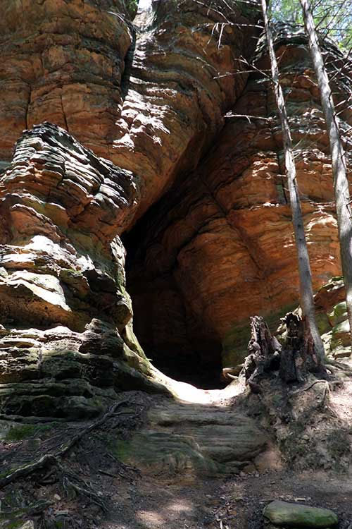 Chapel Cave’s tall sandstone cliffs in Hocking Hills with a narrow rock passage overhead and forest surroundings.