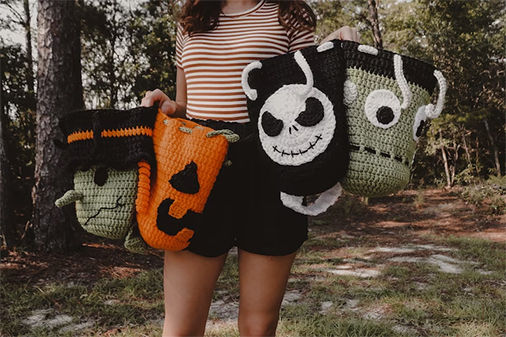 Person holding Halloween crochet baskets featuring Frankenstein, Jack Skellington, and pumpkin designs.