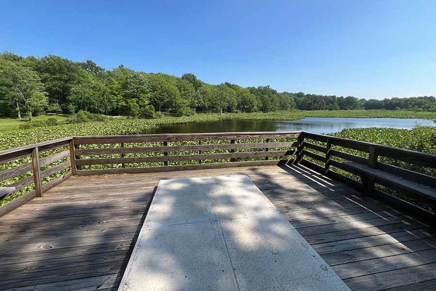 Concrete disc golf tee pad overlooks the lake at Punderson State Park on a clear summer day.