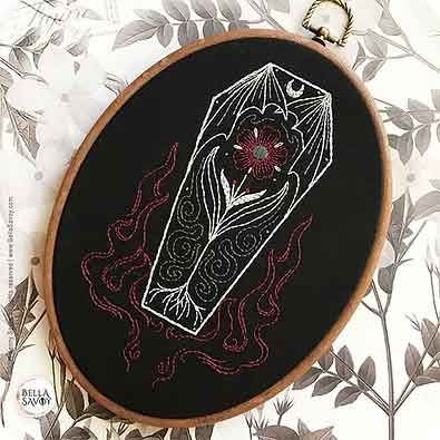 Halloween embroidery coffin design with floral detail and swirling red flames on a black background by Bella Savoy.