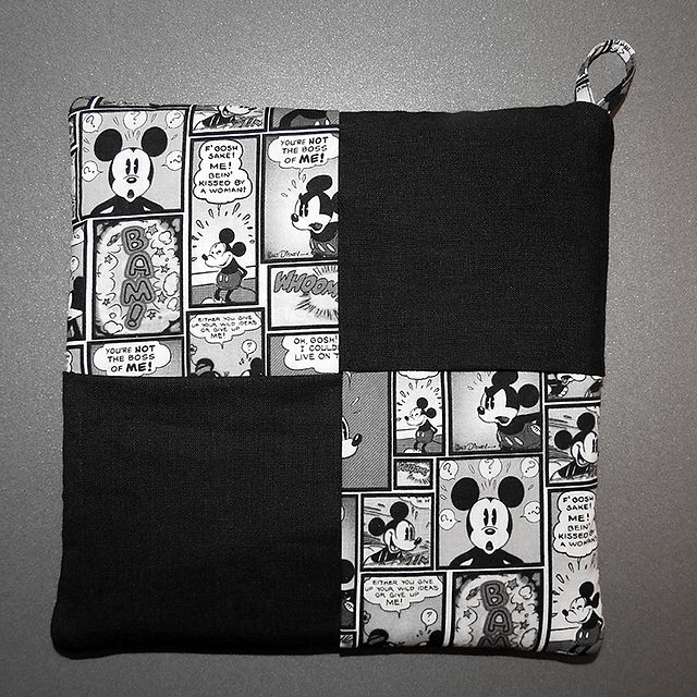 Completed hot pad featuring Mickey Mouse comic panels and black fabric, showcasing how to sew a hot pad with a loop.