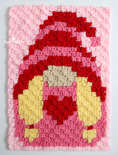 Valentine's Day gnome crochet blanket with a red and pink hat, holding a heart, created using a corner-to-corner crochet technique.