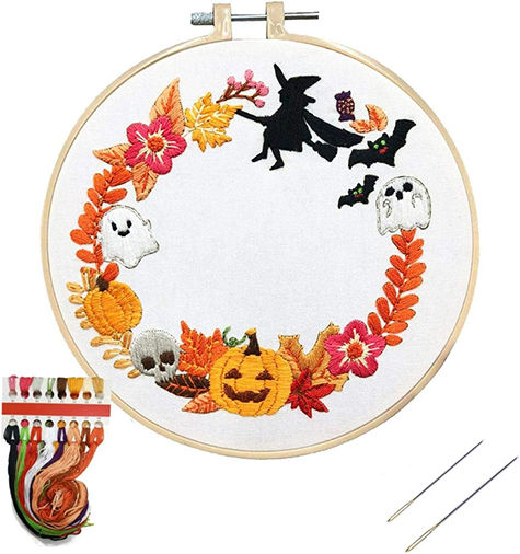 Halloween embroidery kit with a wreath of pumpkins, ghosts, leaves, and a witch flying over a jack-o'-lantern.