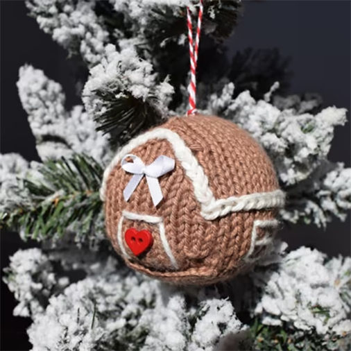 Round knitted gingerbread house ornament with heart and bow details, an adorable free gingerbread house knitting pattern.