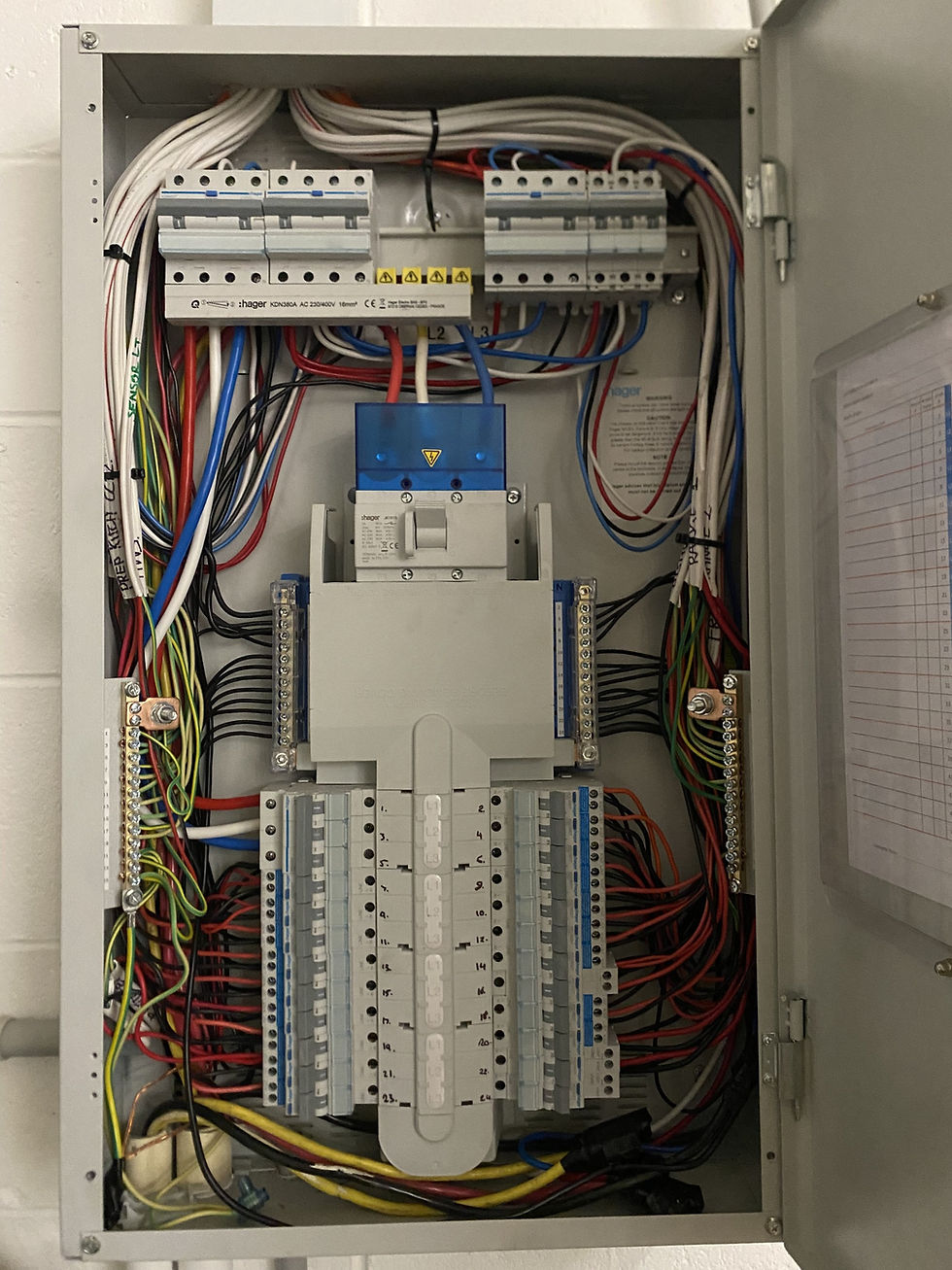 Row of industrial electrical control panels with black switches and glowing red indicator lights, shot in shallow focus.