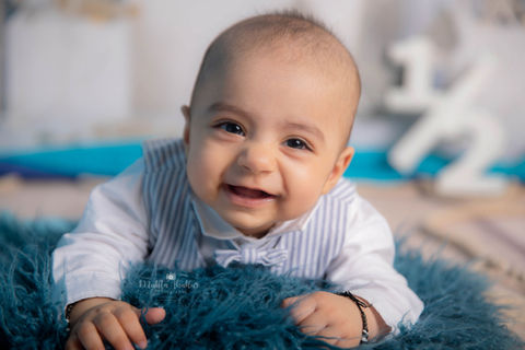 Smiling baby in formal wear on a blue fuzzy blanket. baby photographer in mumbai