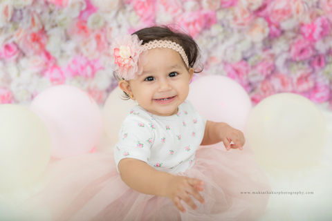 Smiling baby girl in pink tutu with flower headband and balloons, BABIES one year old baby girl photoshoot mumbai