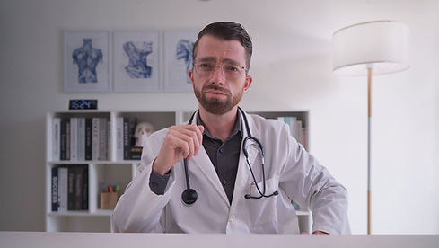 A professional German spokesperson sits in a doctor's office and wears a lab coat.