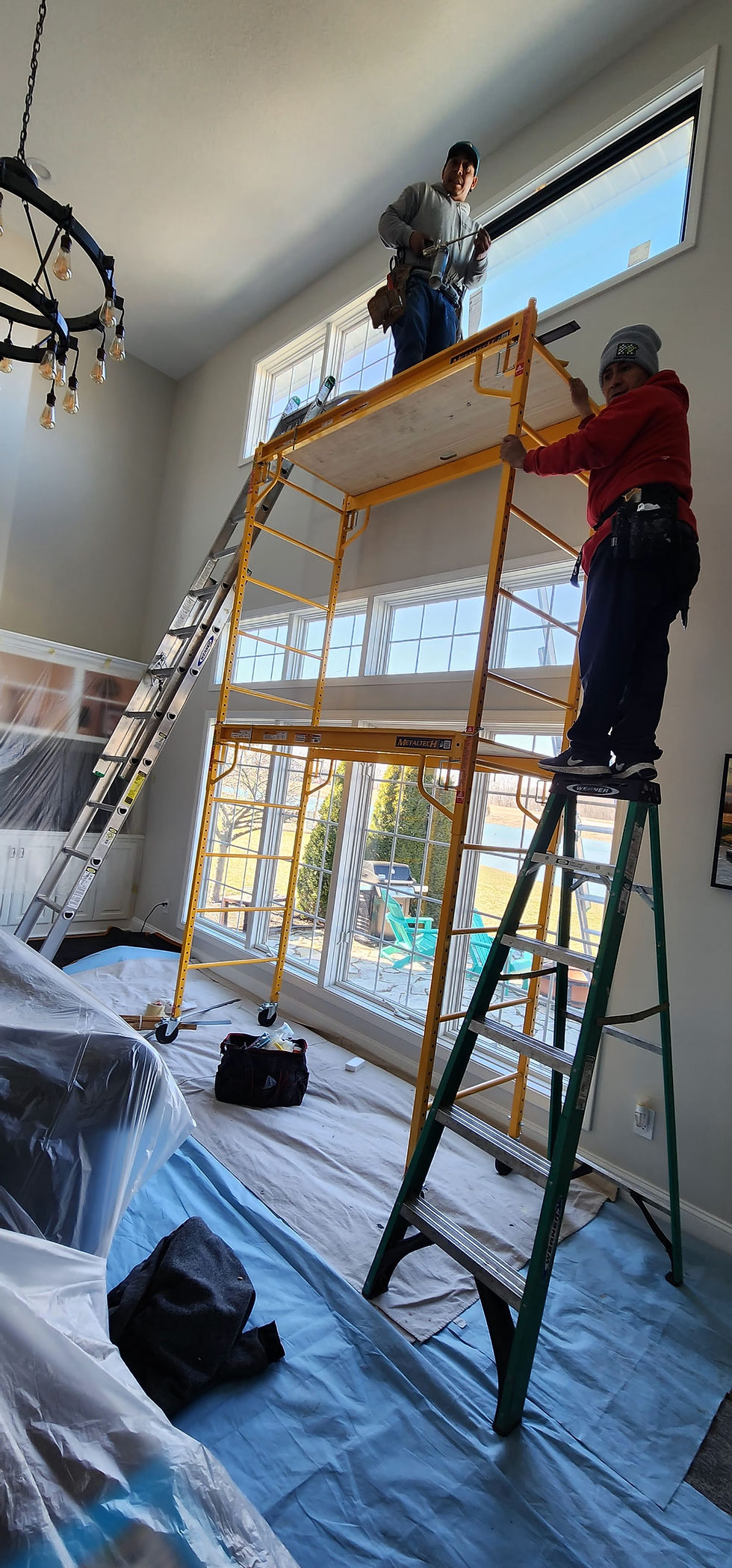 Workers on scaffolding providing window and door installation services.
