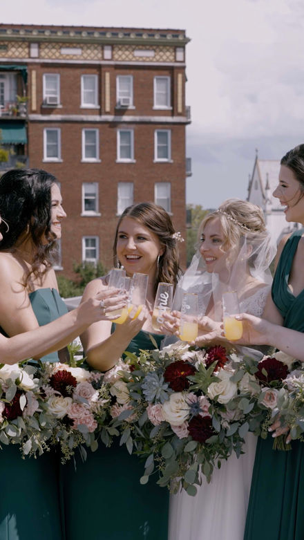a bridal party celebrating on a rooftop in savannah georgia  with the cathedral of st john the baptist in the background.